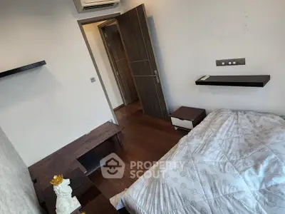 Cozy bedroom with modern decor and wooden flooring, featuring a comfortable bed and stylish shelving.