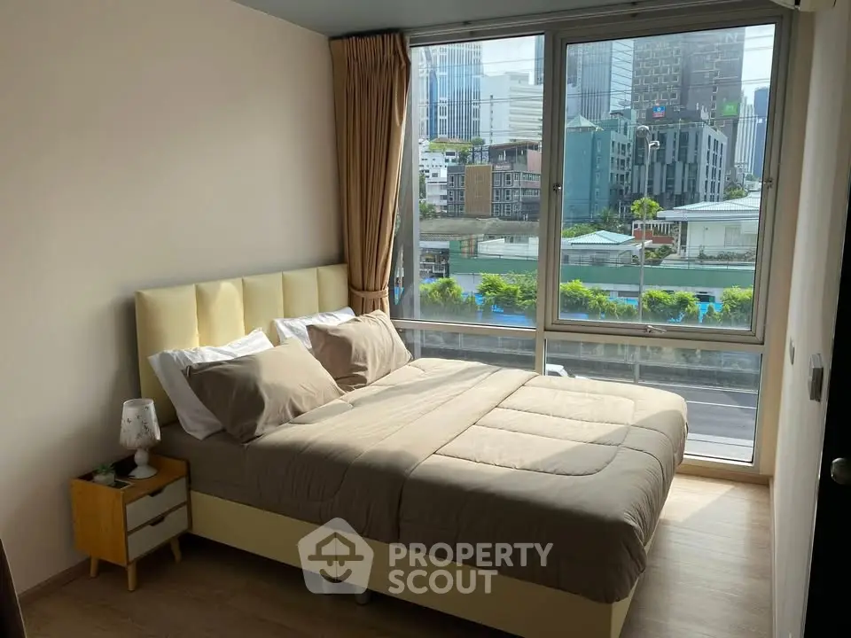 Modern bedroom with large windows offering stunning city views in a high-rise apartment.