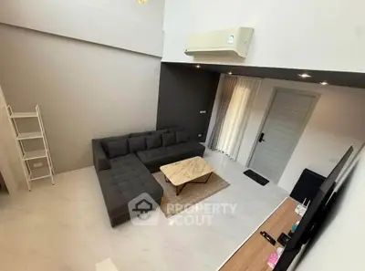 Modern living room with sleek furniture and high ceiling, featuring a stylish sectional sofa and marble coffee table.