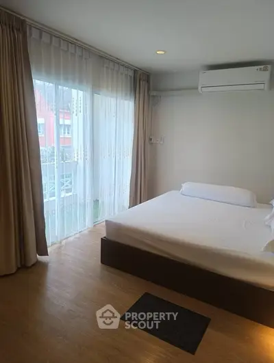 Spacious bedroom with large windows and modern air conditioning unit.
