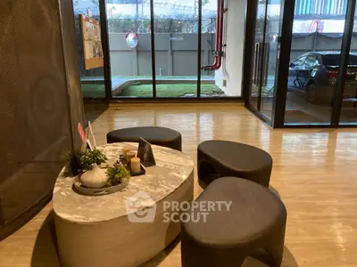 Modern building lobby with stylish seating and glass doors leading to outdoor area.