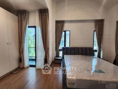 Spacious bedroom with large windows and modern furnishings, offering natural light and comfort.