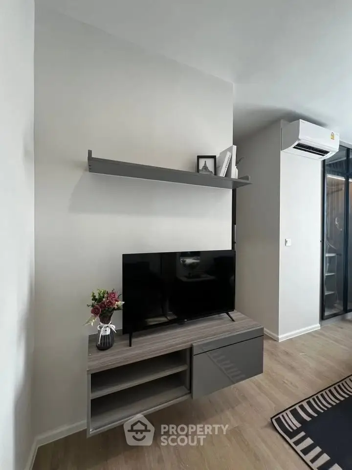 Modern living room with sleek TV stand and wall shelf, featuring stylish decor and air conditioning.