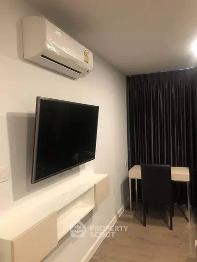 Modern study room with wall-mounted TV and air conditioning, featuring sleek furniture and dark curtains.