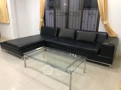 Modern living room with sleek black leather sofa and glass coffee table, perfect for stylish urban living.