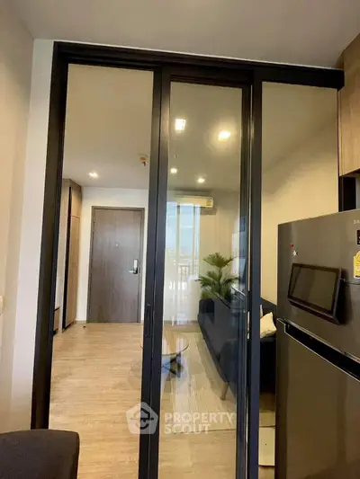 Modern apartment interior with sliding glass doors and sleek kitchen appliances.