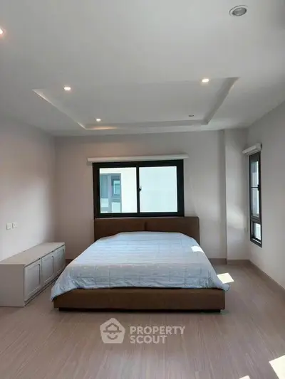 Spacious modern bedroom with large windows and elegant lighting, perfect for relaxation and comfort.