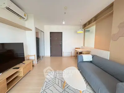 Modern living room with stylish furniture and natural light, featuring a cozy sofa and sleek TV setup.