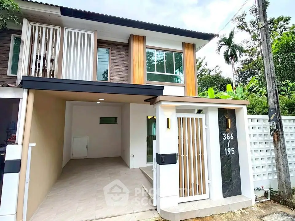 Modern two-story house with sleek design and spacious carport in a lush green setting.