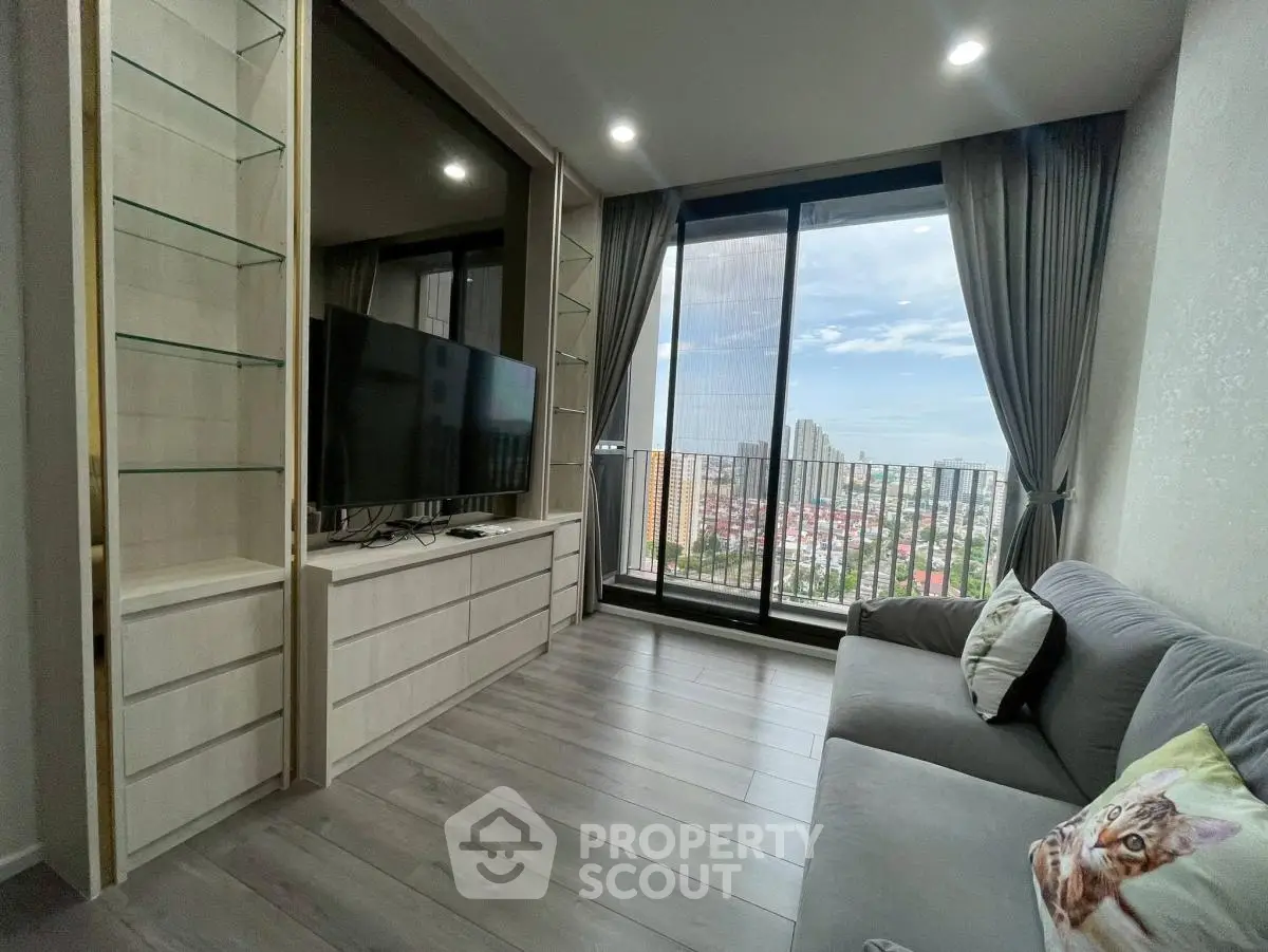 Modern living room with large window and city view, featuring sleek furniture and cozy decor.
