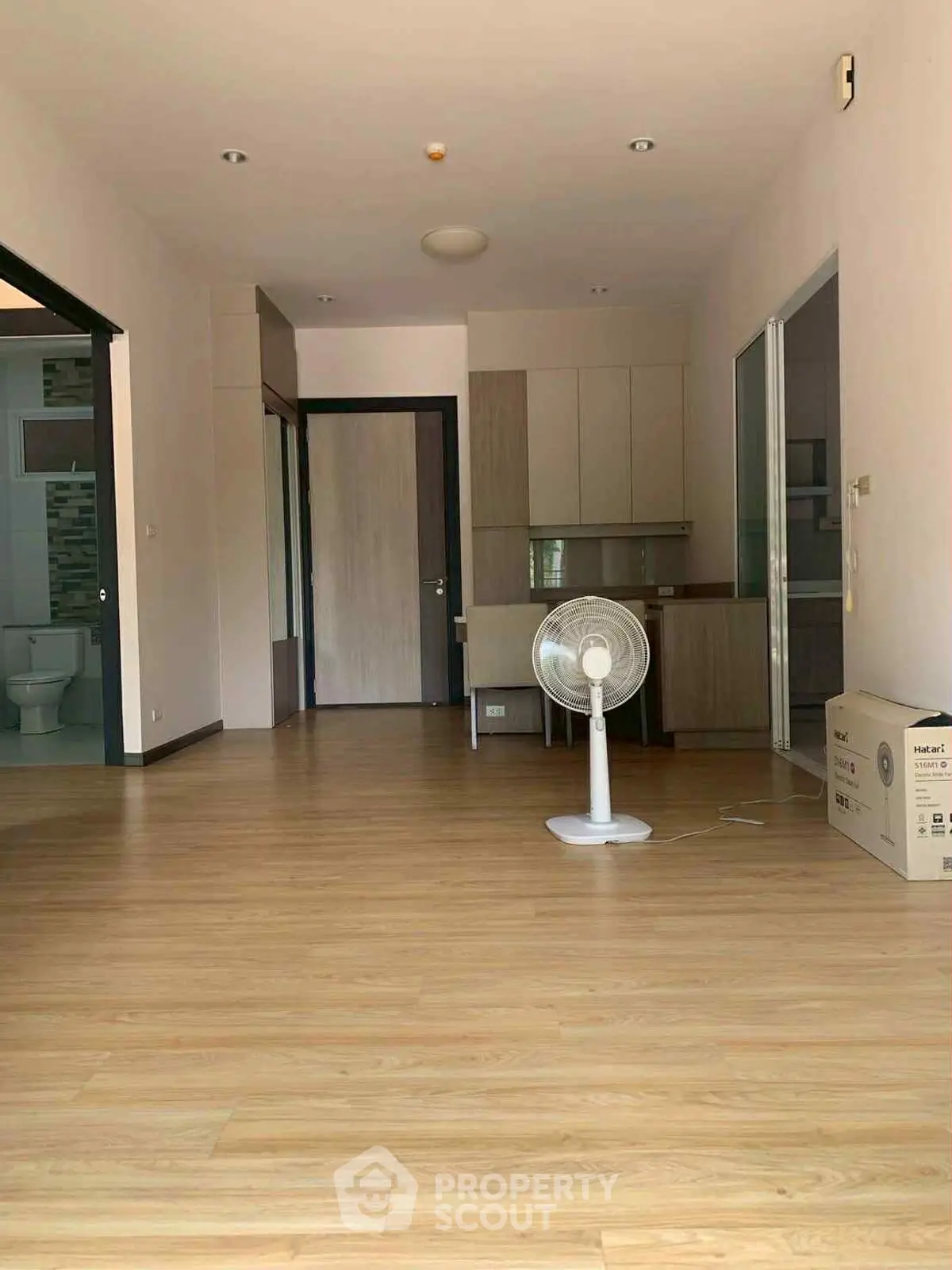 Spacious open-plan living area with wooden flooring and modern kitchen setup.