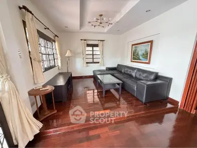 Spacious living room with elegant hardwood floors and modern leather sofa, perfect for relaxation and entertainment.