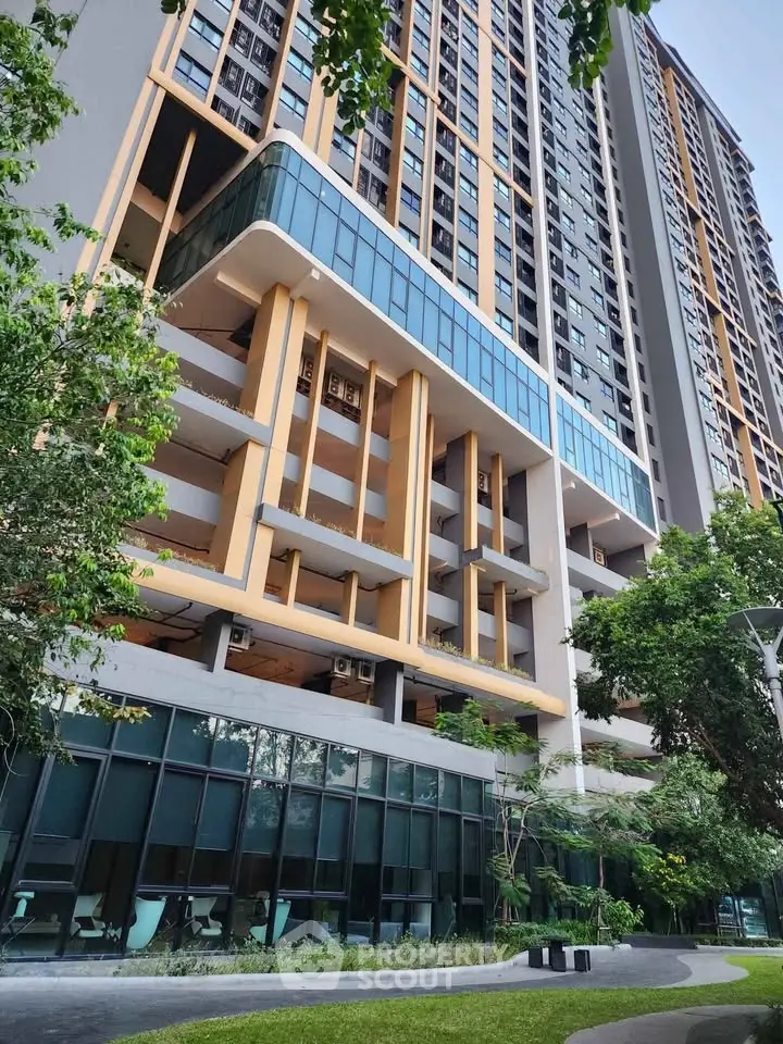 Modern high-rise building with sleek glass facade and lush greenery, showcasing urban living at its finest.
