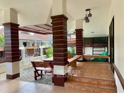 Charming covered patio with wooden seating and tiled flooring in a suburban home.