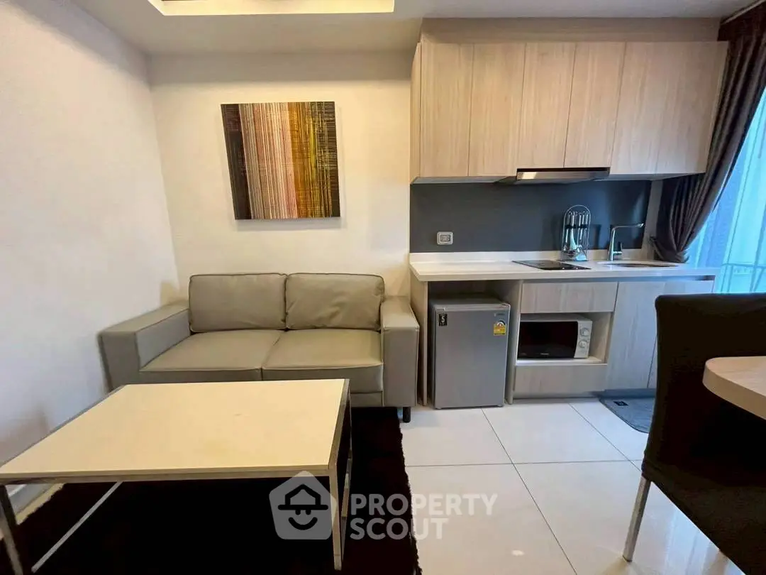 Modern compact living room with kitchenette, featuring sleek cabinetry and cozy seating area.