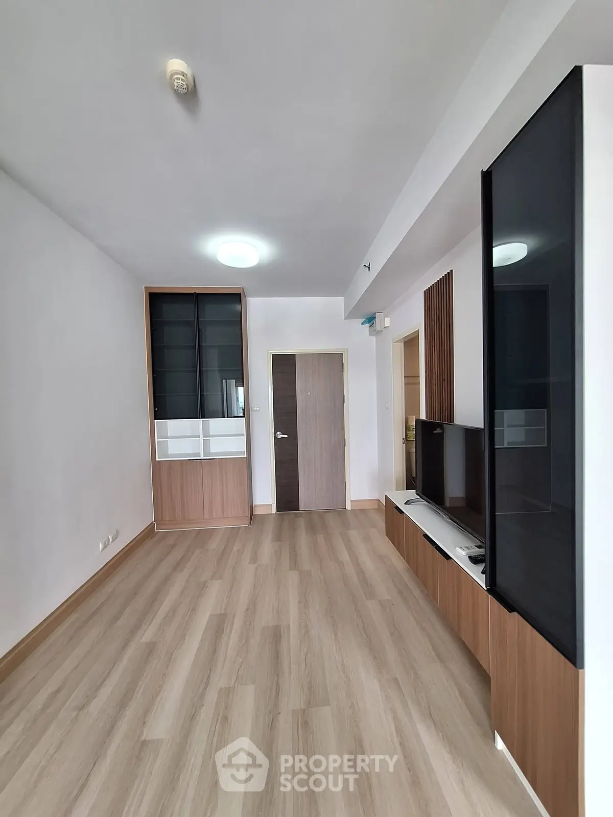Spacious modern living room with sleek wooden flooring and built-in storage units.
