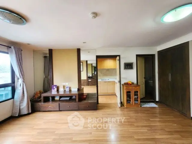 Spacious living room with wooden flooring and modern decor in a bright apartment.