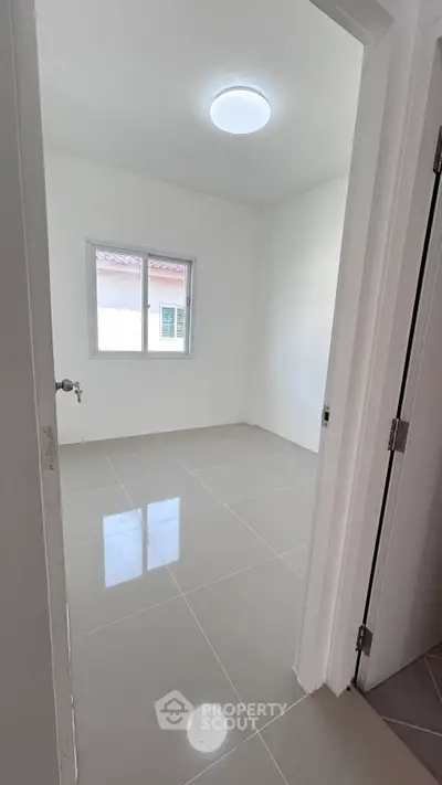 Bright empty room with tiled floor and window, perfect for customization.