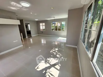 Spacious sunlit living room with large windows and modern tile flooring