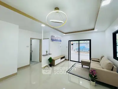 Modern living room with elegant lighting and cozy seating area, featuring large windows for natural light.
