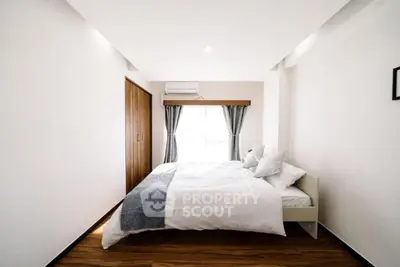 Bright minimalist bedroom with cozy bed and wooden flooring