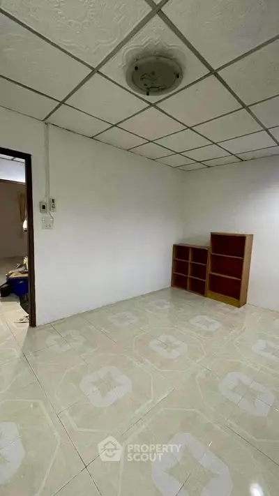 Spacious empty room with tiled floor and ceiling light, ready for customization.