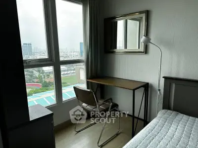 Cozy bedroom with city view, featuring a desk and chair by the window, perfect for work or study.