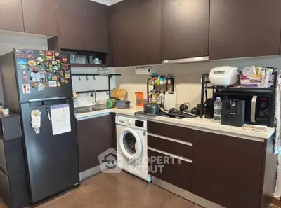 Modern kitchen with dark cabinets, washing machine, and appliances for efficient living.