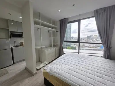 Modern bedroom with city view and open kitchen layout in high-rise apartment.