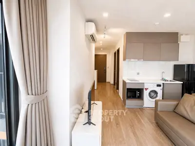 Modern apartment interior with open layout, featuring a cozy living area and compact kitchen with appliances.
