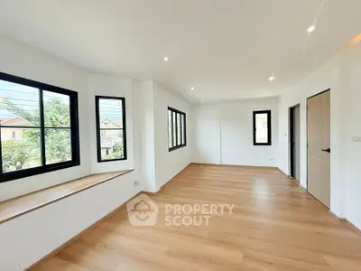 Spacious and bright living room with large windows and wooden flooring