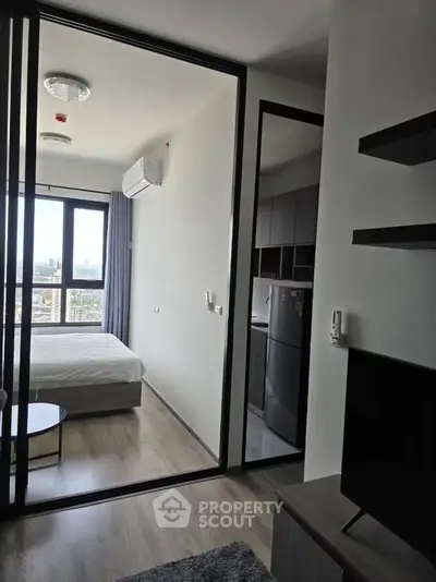Modern apartment with sleek bedroom and living area, featuring large windows and stylish furnishings.