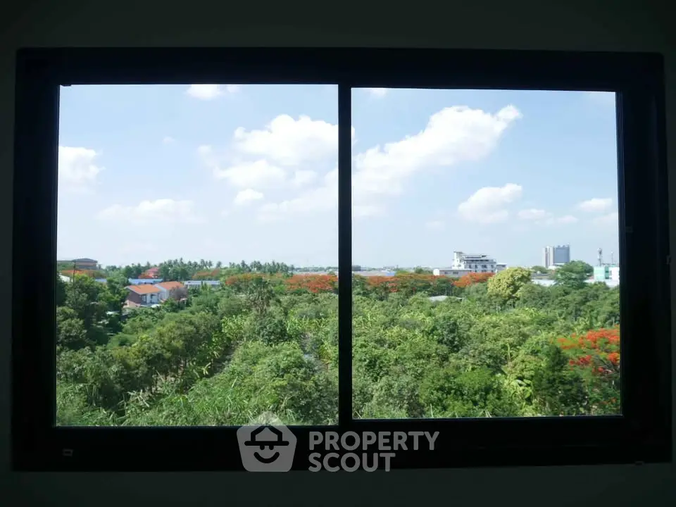 Stunning window view of lush greenery and cityscape under a clear blue sky.