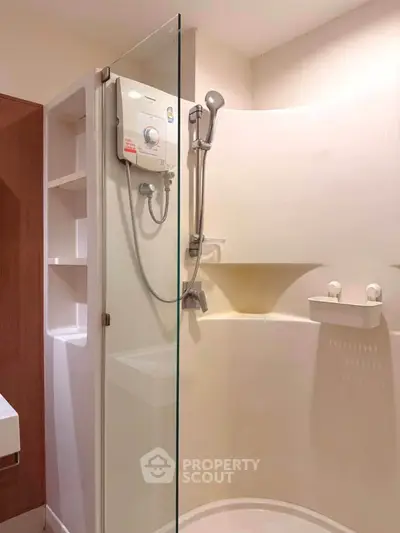 Modern bathroom with glass shower enclosure and built-in storage shelves.