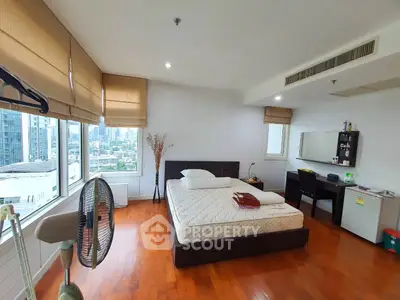 Spacious bedroom with city view and modern furnishings in a high-rise apartment.