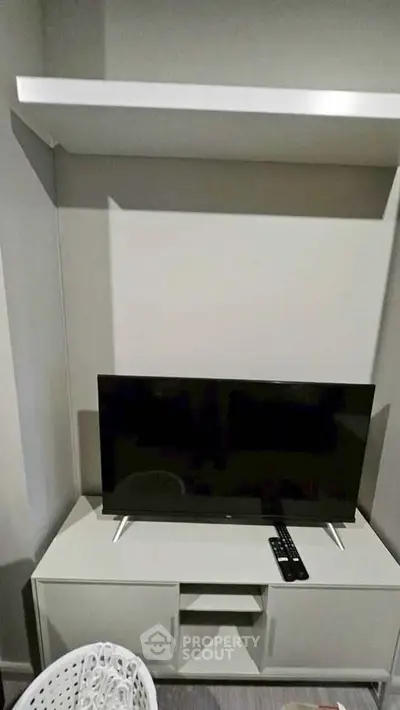 Modern living room setup with sleek TV stand and wall-mounted shelf, perfect for minimalist decor.