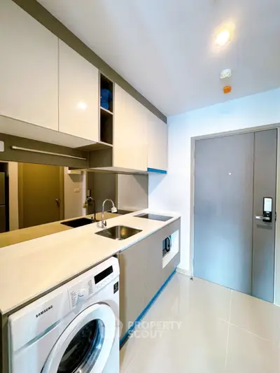 Modern kitchen with sleek cabinetry and built-in washing machine in a stylish apartment.