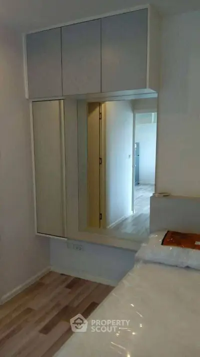 Modern bedroom with sleek built-in wardrobe and mirror reflecting natural light.