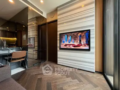Modern living room with stylish decor and built-in TV, featuring elegant wood flooring and sleek kitchen area.