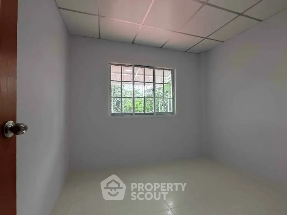 Spacious empty room with large window and tiled floor, perfect for customization.