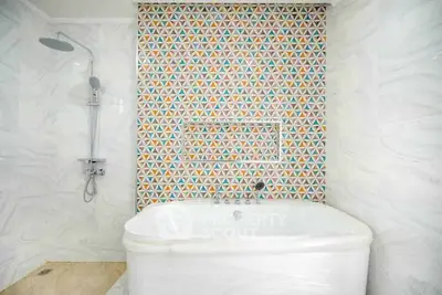 Stylish bathroom with modern bathtub and colorful geometric tile wall