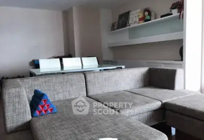 Modern living room with stylish gray sectional sofa and sleek shelving.