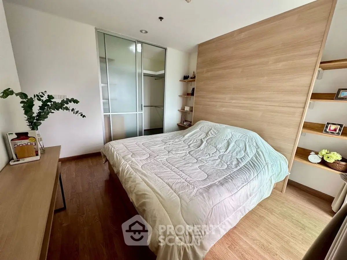 Cozy bedroom with wooden flooring and sliding closet doors in modern apartment.