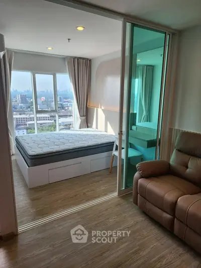 Modern bedroom with city view, featuring a comfortable bed and cozy seating area.