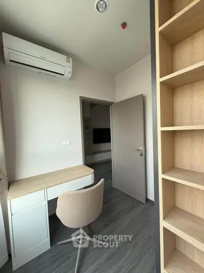 Modern study room with sleek desk, chair, and built-in shelving, featuring air conditioning and minimalist design.
