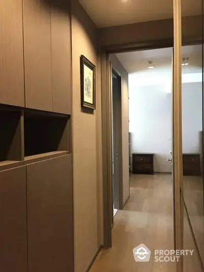 Modern hallway leading to a cozy bedroom with wooden flooring and built-in storage.