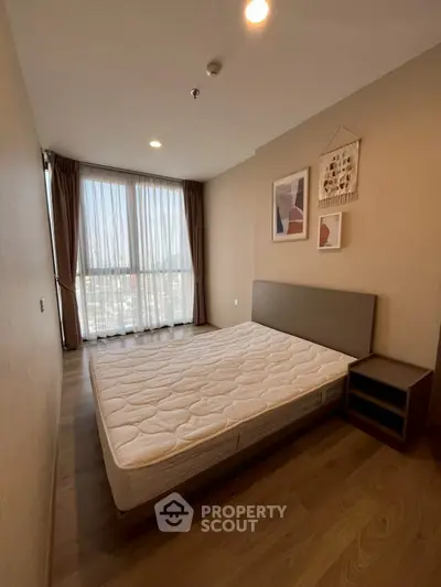 Spacious bedroom with large window and modern decor in a high-rise apartment.