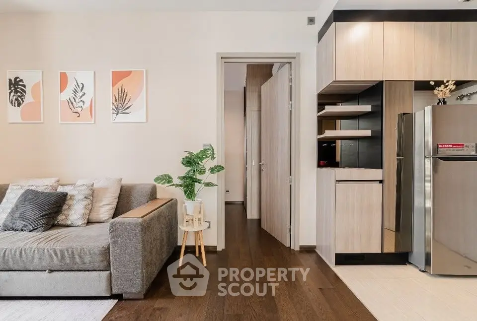 Modern living room with stylish decor and sleek kitchen area, featuring a cozy sofa and contemporary artwork.