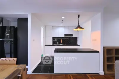 Modern kitchen with sleek black countertops and stylish lighting in open layout design.