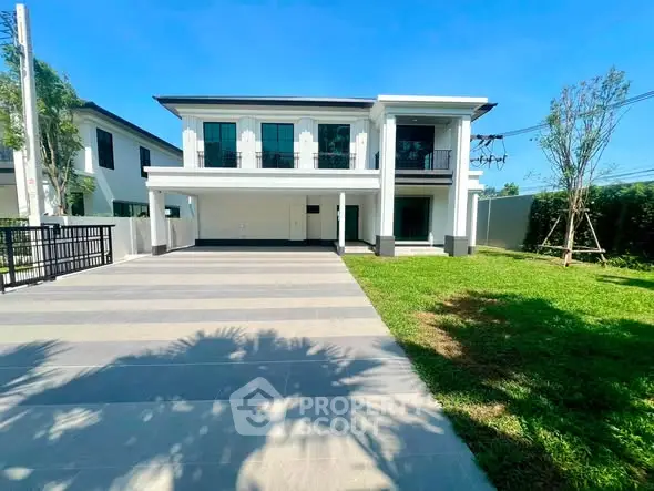 Modern two-story house with spacious driveway and lush green lawn under clear blue sky.